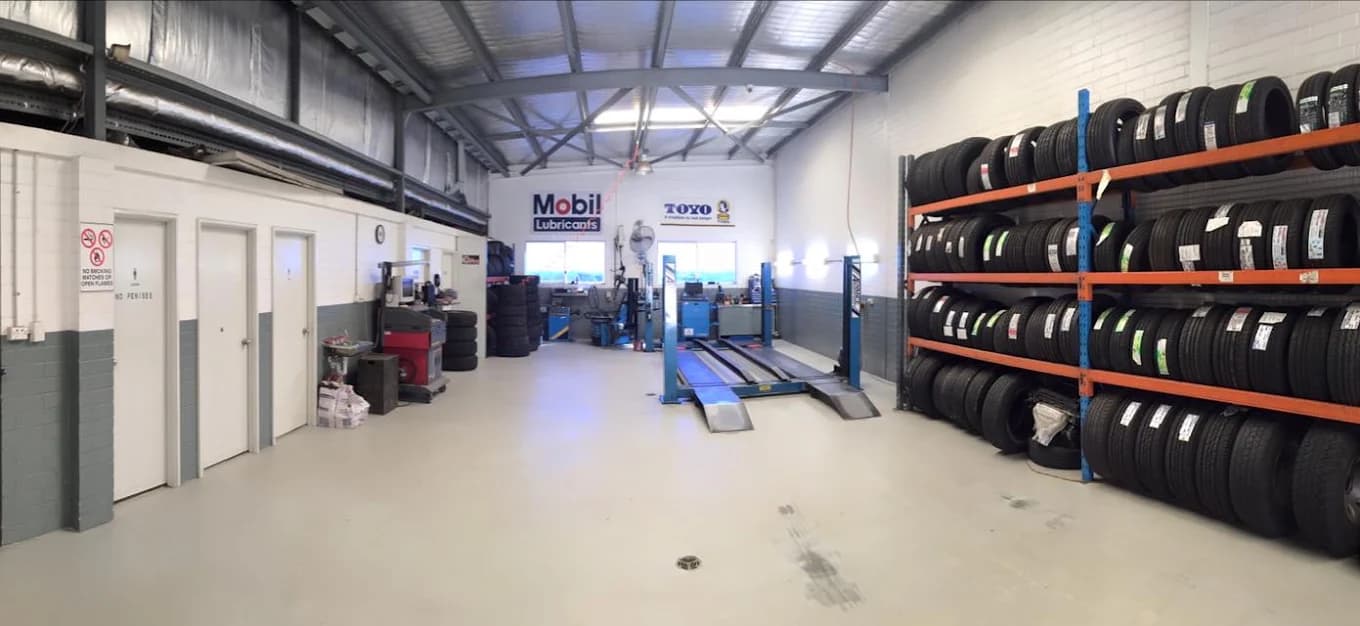 Inside The Ultimate Tyre and Brake workshop in Balcatta, with tyres racked and a vehicle on the hoist